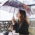 Femme avec un parapluie assis à une terrasse