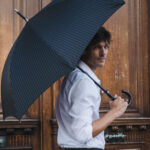 Homme avec un parapluie devant une porte en bois