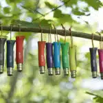 Plusieurs couteaux pliants de couleurs différentes pendus à une branche
