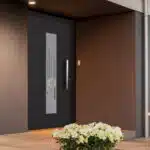 Porte d'entrée noire, avec partie vitrée, fleurs blanches
