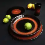 Assiettes noires avec trait rouge présentées avec des citrons sur fond noir