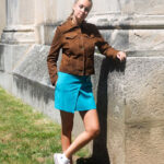Femme en veste en cuir marron et jupe bleue