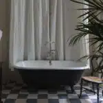 baignoire ancienne devant rideau blanc sur sol blanc et noir