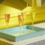 Coupes à champagne sur un plateau devant un mur jaune