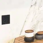 Prise électrique noir moucheté sur mur marbré