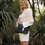 Sac noir porté en bandoulière par une femme élégnate