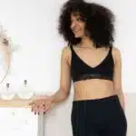 Femme en brassière noire accoudée à une commode