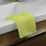 Une serviette couleur pomme, posée sur un rebord de lavabo