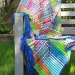 Plaid coloré posé sur un banc en bois en extérieur
