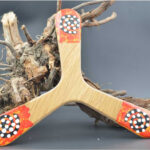 Boomerang en bois décoré posé sur contre une branche