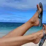 une paire de tongs sur 2 pieds nus sur fond de mer