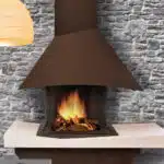 cheminée à foyer ouvert avec un feu allumé, une hotte marron avec mur en pierre en arrière plan