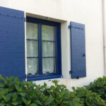 Volets battants bleus, avec rideaux aux fenêtres