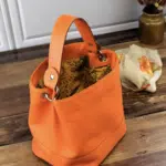 Sac en cuire orange posé à coté d'un foulard