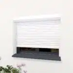 Volet roulant blanc presque fermé sur façade claire