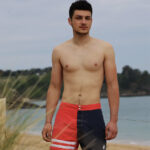 homme torse nu en maillot de bain devant la mer