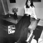 femme assise sur table avec chemisier et jupe longue