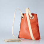 sac à dos haut de gamme en cuir orange, avec bretelles beiges.