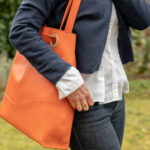 sac haut de gamme en cuir orange porté à l'épaule.