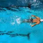 homme avec combinaison et bonnet dans piscine