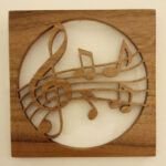 disque découpé dans un carré de bois traversé par une portée musicale en bois