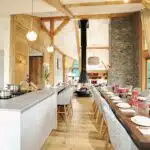 Cuisine ouverte avec grande table dressée-grande cheminée en arrière plan.
