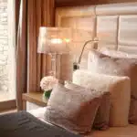 Lit avec coussins roses pastels, bouquet de fleurs sur table de nuit.