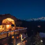 Terrasse éclairée d'un chalet en montagne dans la nuit.