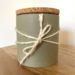 une bougie dans un pot avec un couvercle en liège et une ficelle