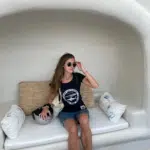Mode éthique : Femme assise sur banquette avec des coussins et avec T-shirt noir