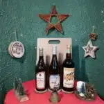 3 bouteilles posées sur une table avec nappe rouge avec décor de fêtes