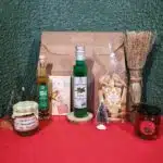 2 pots de confiture, 2 bouteilles et des gâteaux posés sur une nappe rouge