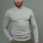 homme avec sweat manche longue gris et pantalon kaki, main droite dans la poche